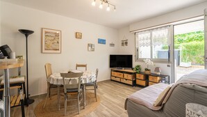 Une pièce confortable avec une table  à manger, des chaises, un téléviseur, un canapé et une grande fenêtre.