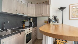 Une cuisine avec des meubles de couleur bois clair, un évier en acier inoxydable, un four à micro-ondes et une cuisinière.
