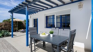 An outdoor patio with a table, chairs, and a potted plant.