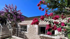 A stone building with a staircase, a tree with purple flowers, and pink bougainvillea. - Villa L'Envie d'Eymet – Eco-efficient haven, cool in summer, cozy in winter (Eymet)