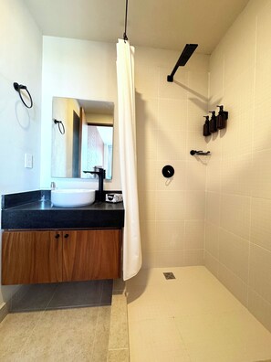 A modern bathroom with a white sink, wooden cabinet, and a shower area with a white curtain. - Condo in Cancun with Pool, Gym and Coworking | Pet friendly, near ZH (Cancún)