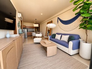 A modern living room with a sofa, coffee table, and a dining area with chairs. - Condo in Cancun with a pool, gym, and coworking space | Pets allowed, near ZH (Cancún)