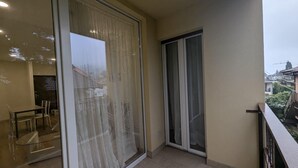 A balcony with a glass door, a sliding glass door, and a view of a residential area.