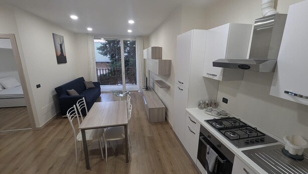 A compact kitchen with a dining area, a sofa, and a view to the outside.