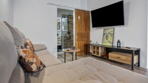 A modern living room with a sofa, a coffee table, a TV mounted on the wall, and a wooden door.