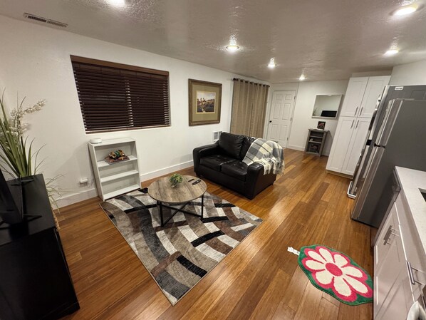 Una sala de estar moderna con un sofá de cuero negro, una mesa de centro y una alfombra estampada.