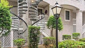 Un bâtiment doté d’un escalier en colimaçon, d’un porche avec une balustrade et d’un lampadaire.