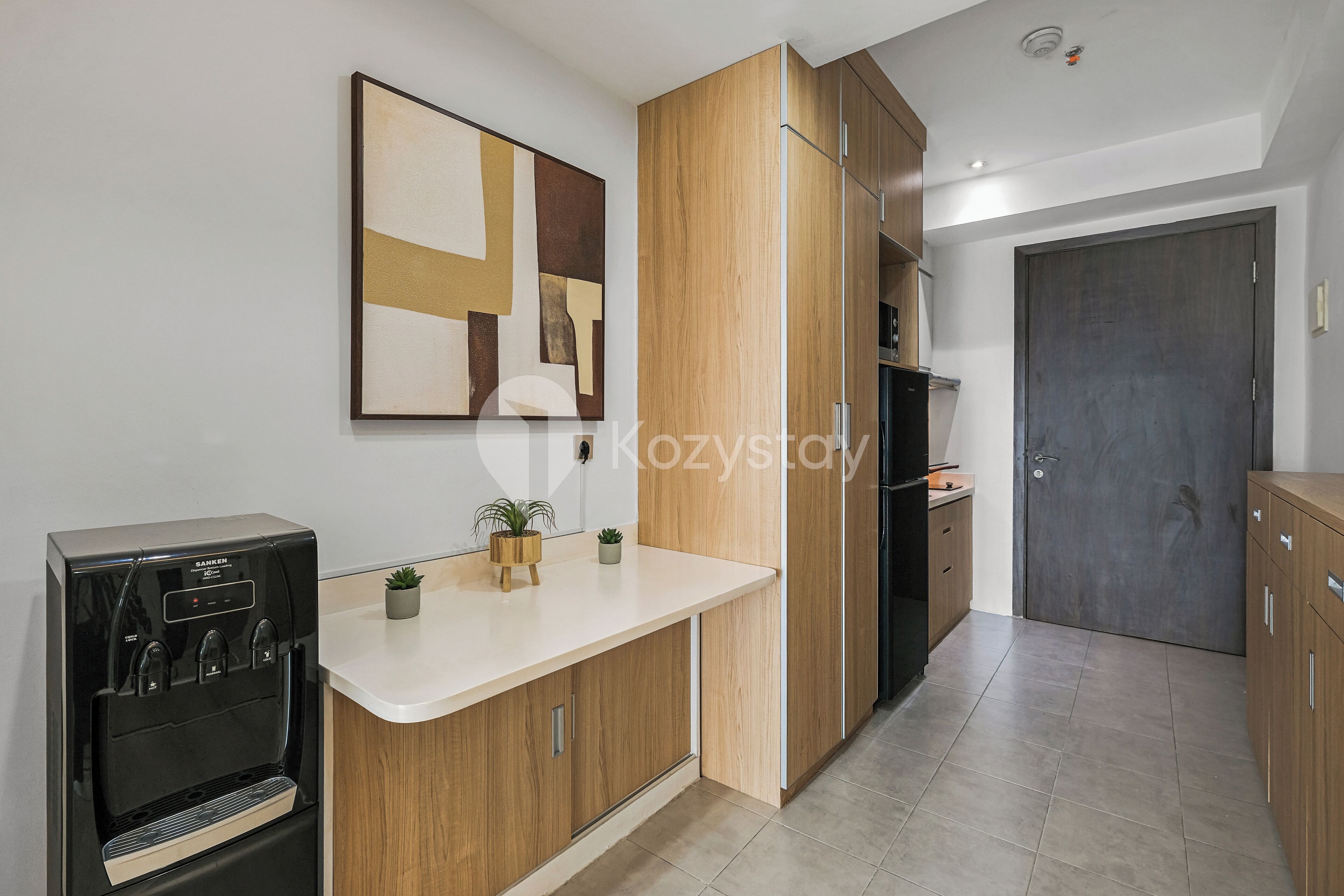 A modern kitchen with wooden cabinets, a built-in stove, and a countertop with a water dispenser.