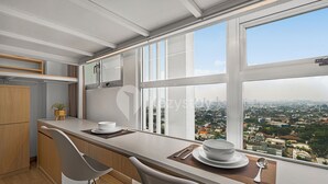 Une cuisine moderne dotée d’une grande fenêtre, d’un coin repas et offrant une vue sur le paysage urbain.