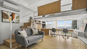 Une chambre moderne de style loft, avec un lit superposé, un canapé gris et un espace bureau.
