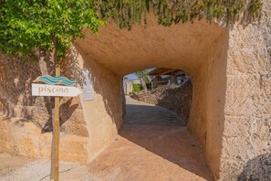 A stone tunnel entrance with a sign reading "piscina".