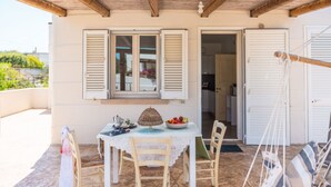 Une terrasse avec une table dressée pour deux personnes, un panier en osier et un saladier rempli de fruits.