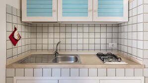 A kitchen with a sink, stove, and tiled backsplash.