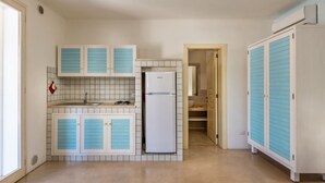 A compact kitchen with white cabinets and a white refrigerator.