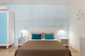 A bedroom with a bed, two bedside tables, a nightstand, a wardrobe, and a wall-mounted light fixture. - Cava Li Santi Residence - Monolocale 2 Int 11 (Santa Caterina)
