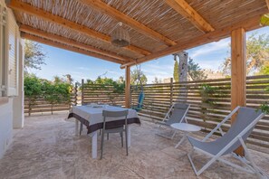 Um pátio externo com mesa, cadeiras, uma cadeira suspensa e um cercado de madeira.