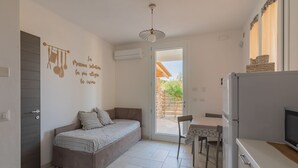 Una cocina compacta con sofá, una mesa de comedor y refrigerador.
