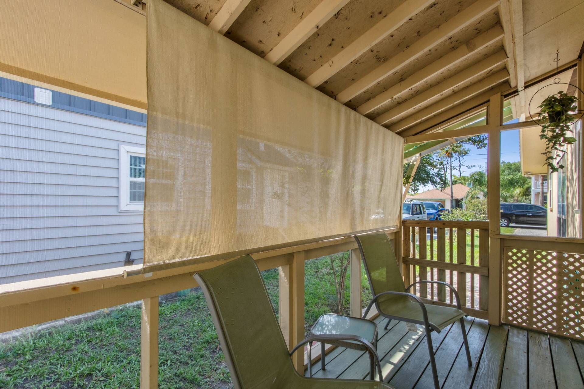 A covered porch with a wooden railing, a table, and two chairs.