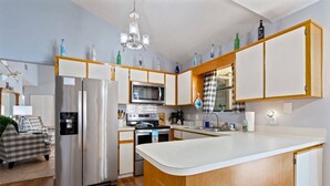 A compact kitchen with a central island, built-in appliances, and a microwave. - 3BR Turtle Hut - Beach House w/ Fenced Yard & Firepit (Jacksonville Beach)
