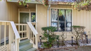 A two-story house with a front porch, a staircase, and a large window. - 3BR Turtle Hut - Beach House w/ Fenced Yard & Firepit (Jacksonville Beach)