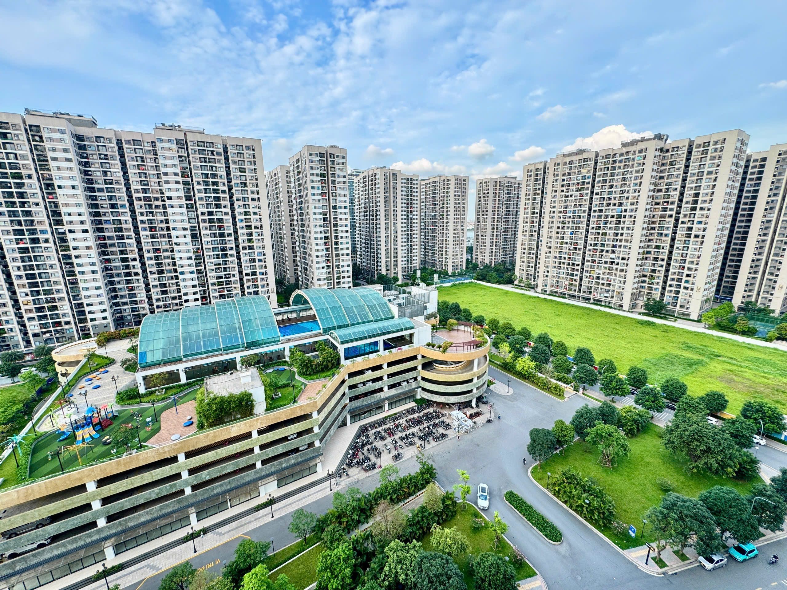 A high-rise residential building complex with multiple apartment buildings, a central courtyard with a swimming pool, and a parking structure.