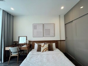 A hotel room with a bed, a desk, a chair, and a wardrobe.