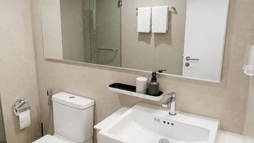 A modern bathroom with a toilet, sink, and shower.