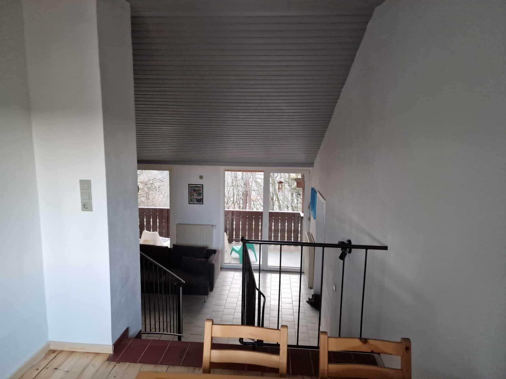 Une pièce avec un escalier menant à un balcon, un radiateur et une vue sur l’extérieur.