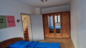 A bedroom with a wooden bed, a wardrobe, and a staircase leading to another room.