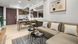 A modern living room with a sofa, coffee table, and a dining area with a chair and table. - Solaya by Kozystay - Kuningan (Jakarta)