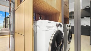 A modern laundry room with a Samsung digital washer and dryer, wooden cabinetry, and a large mirror. - Solaya by Kozystay - Kuningan (Jakarta)