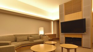 A modern living room with a sofa, two coffee tables, and a flat-screen TV mounted on the wall.
