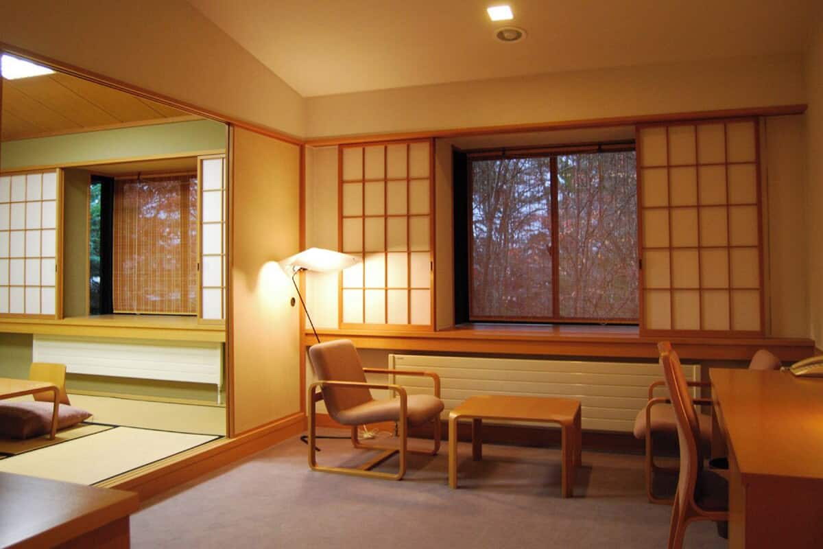 A traditional Japanese-style room with tatami flooring, low tables, and sliding shoji screens.