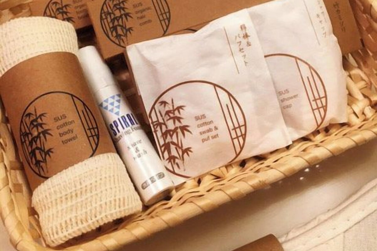 A wicker basket containing various items including a white towel, a bottle, and several paper bags with bamboo designs.