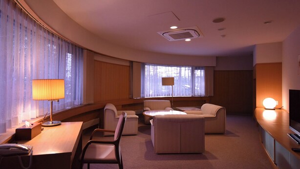 Une chambre d’hôtel équipée d’un bureau, de deux chaises, d’un canapé, d’une télévision et d’une lampe.
