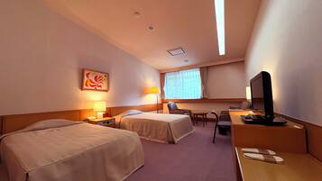 A hotel room with two beds, a desk with a computer, a chair, and a TV.