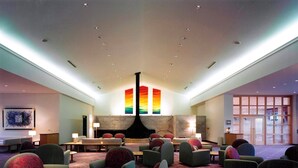 A spacious lobby with multiple seating areas, a central fireplace, and a large window with a view.