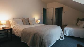Une chambre à coucher avec un grand lit, deux tables de chevet et une porte donnant sur une autre pièce.