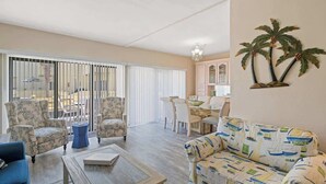 A living room with a sofa, armchairs, a coffee table, and a dining area with chairs and a table. - Peaceful Paradise - Boat Slip, Pool & Beach Access (Navarre)