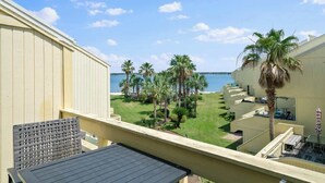 A balcony with a view of the sea, palm trees, and a pool area. - Peaceful Paradise - Boat Slip, Pool & Beach Access (Navarre)