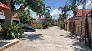 Una calle residencial con casas, un coche aparcado y palmeras.