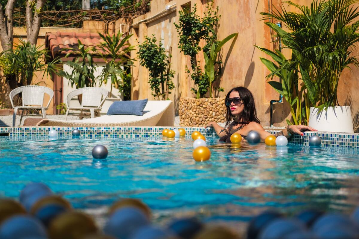 A swimming pool with lounge chairs and potted plants around it.