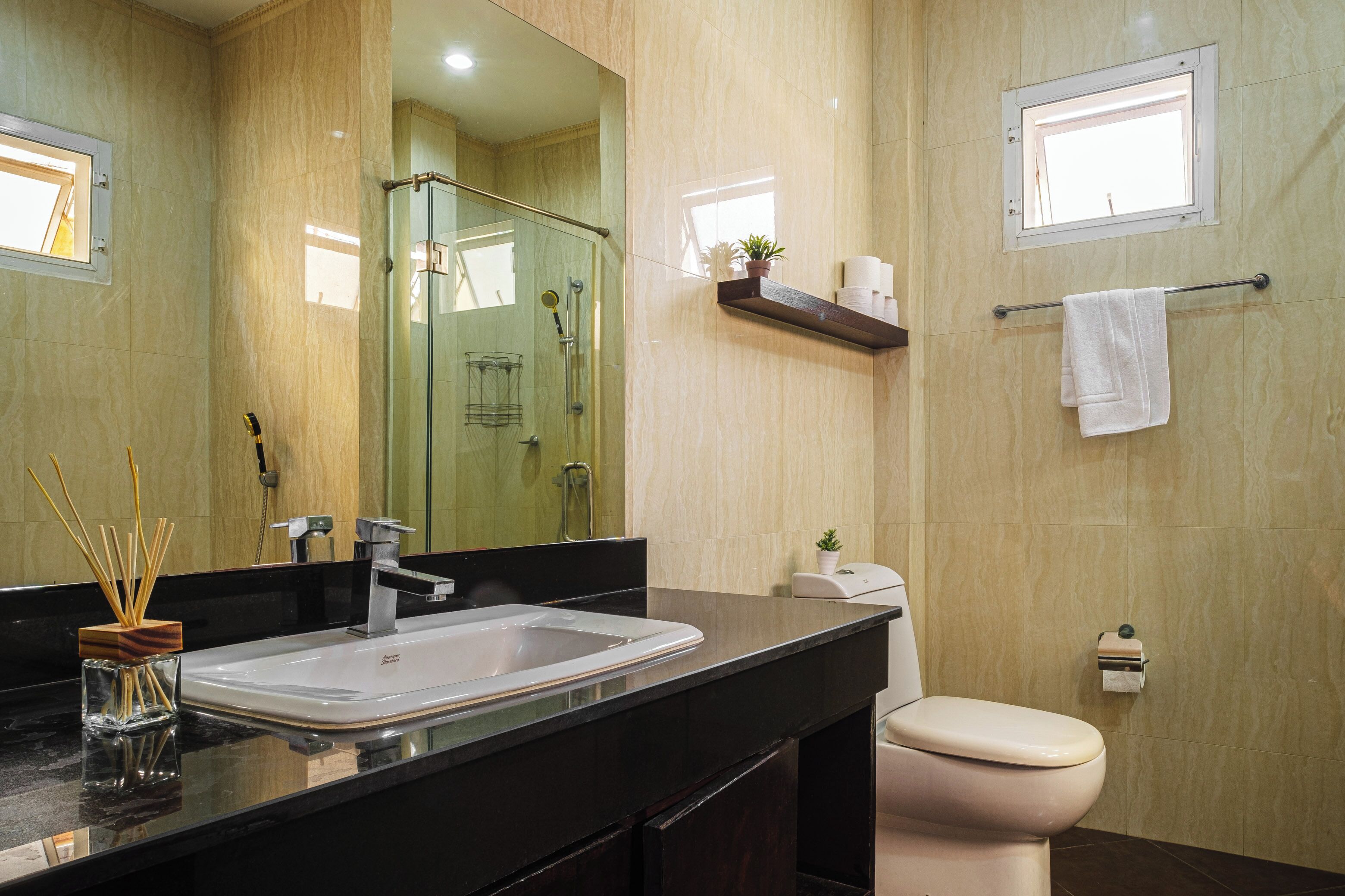 A modern bathroom with a large mirror, a sink, a toilet, and a glass-enclosed shower.