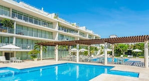 Hotel com piscina, área de estar externa e um edifício com várias andares e sacadas.
