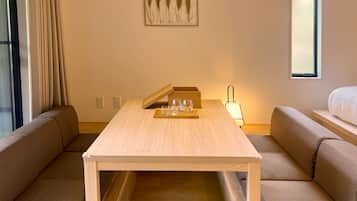 A hotel room with a wooden table, two sofas, a bed, and a window.