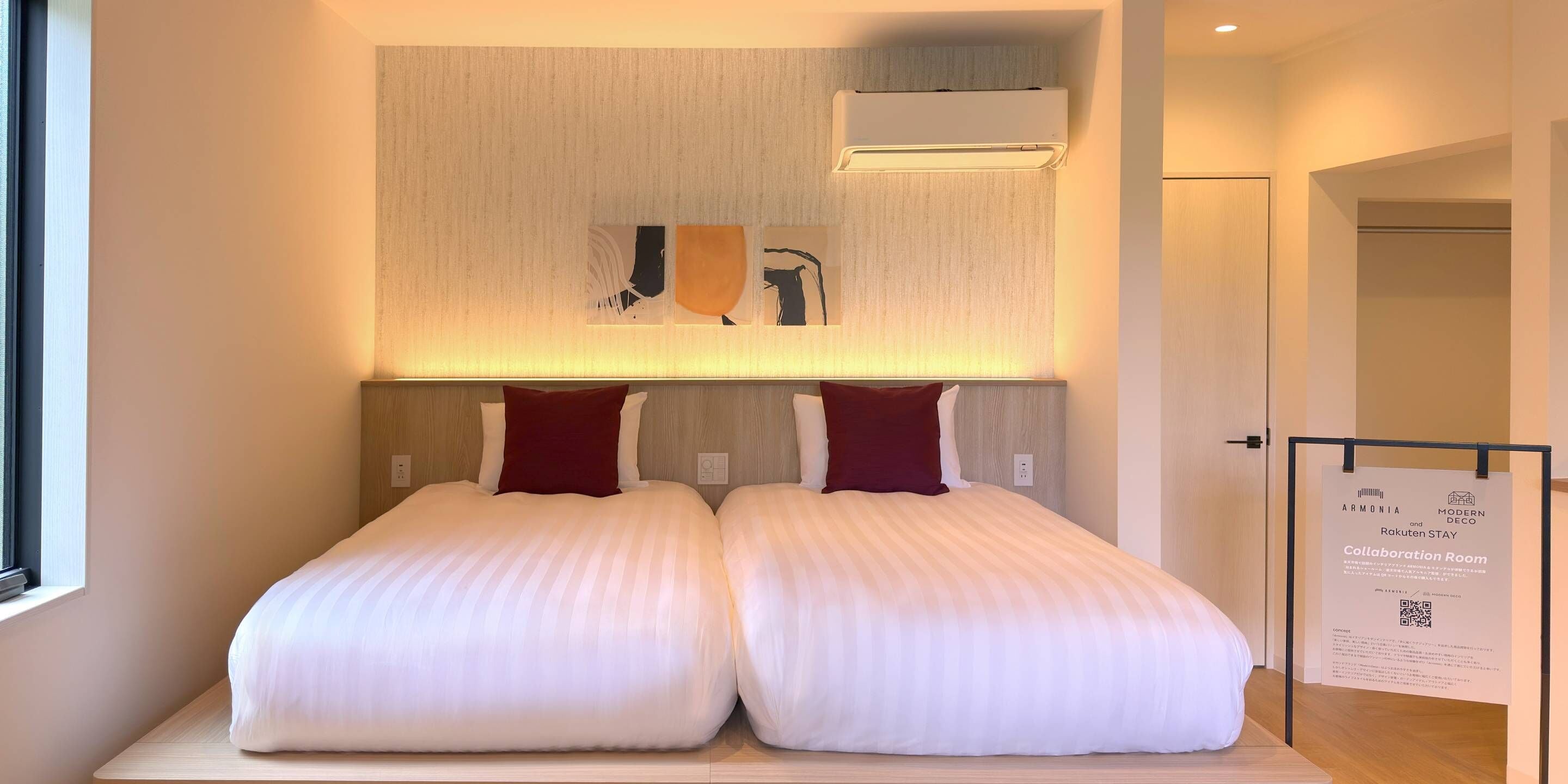 Una habitación de hotel moderna con dos camas, un cabecero de madera y un aire acondicionado de pared.