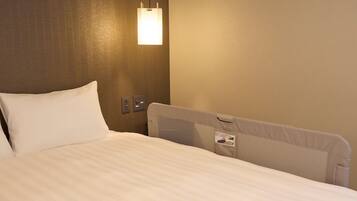 Una habitación de hotel con una cama bien hecha, una lámpara fijada en la pared y un panel de control en la pared.