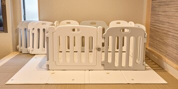 Habitación con una puerta de seguridad para bebés, un felpudo y suelo de madera.