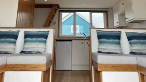 Un dormitorio estilo loft con techo inclinado, vigas de madera y una zona de cocina integrada.