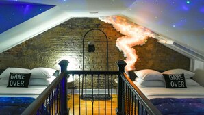 Une chambre confortable située sous les toits, avec un plafond en pente, des murs en briques apparentes et une cheminée.